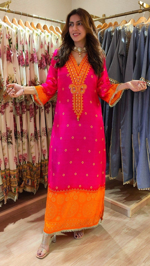 Woman in a bright pink and orange traditional outfit standing in a clothing store.