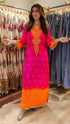 Woman in a bright pink and orange traditional outfit standing in a clothing store.